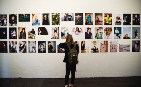 Eine Bildgalerie auf dem Reeperbahnfestival. Davor steht eine junge Frau und schaut die verschiedenen Bilder an.